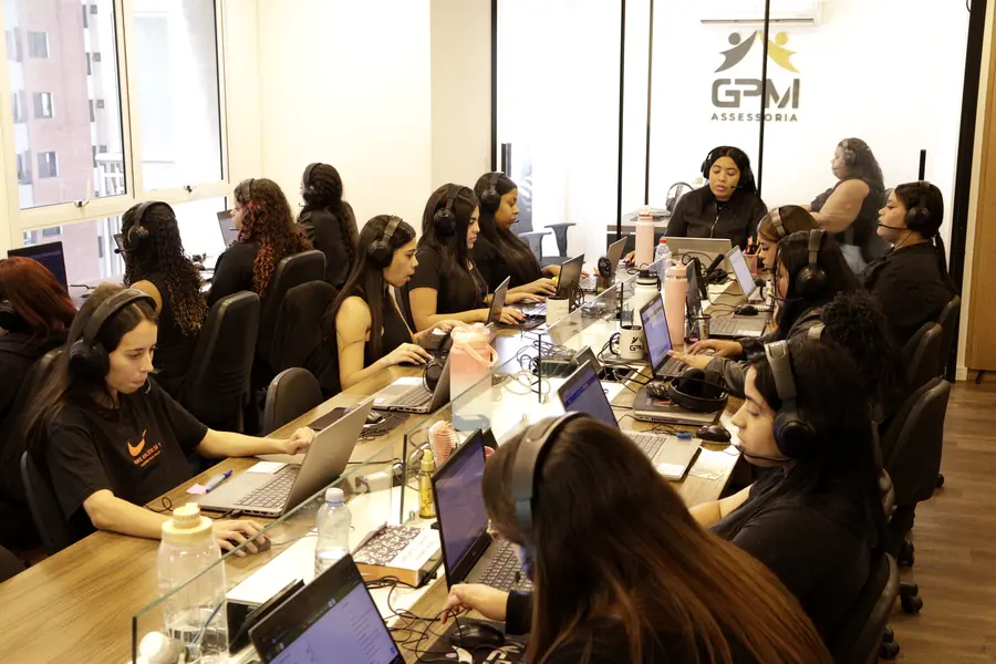 Escritório da GPM em São Paulo, com a equipe em atendimento e o logo da empresa na parede ao fundo
